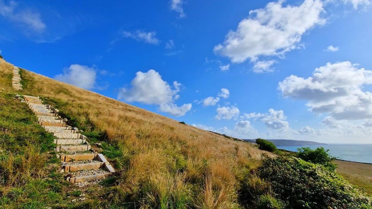 View looking up hill with steep steps, and the sea to the right.